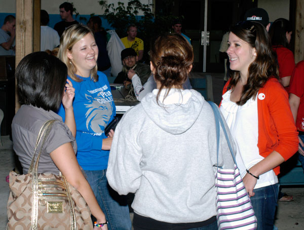 Erin Datteri, assistant director of student activities for Greek life and leadership (in blue shirt), visits with Katie Weitkunat, Alpha Sigma Alpha representative (right) and others outside College West Apartments.