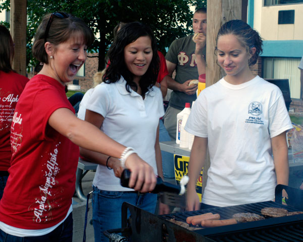 Alpha Sigma Alpha's Katie Buhrman helps out College West grillmasters (and Resident Assistants) Liz Rutt, center, and Alyssa Giedroc, right.
