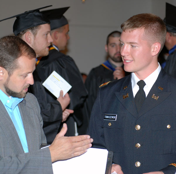 Official photographer Luther Aungst instructs serviceman/graduate Patrick Tomaszewski how to time his presidential handshake for the best commencement memento.