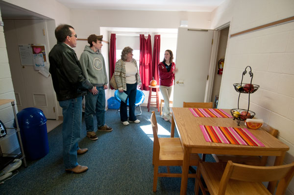 A resident student opens her door to a campus-housing tour.