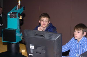 Students participating in Technology Day give commands to a robotic arm.
