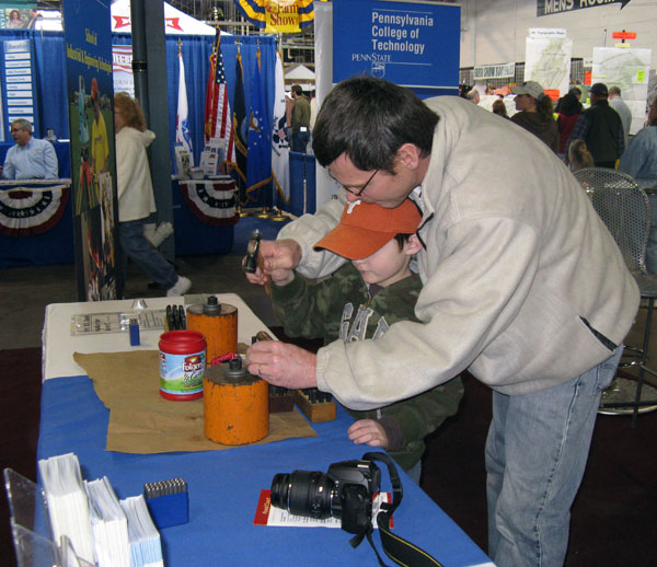 A father and son make an ID tag  and a Farm Show memory  during a stop at the Penn College booth.