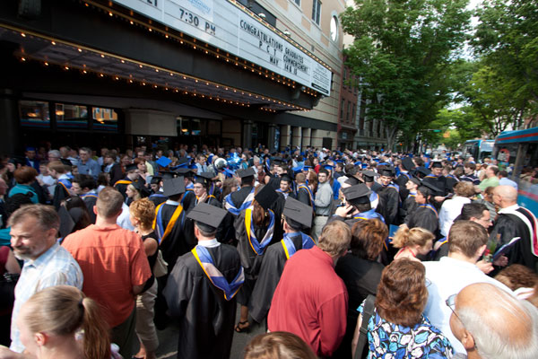 Graduates pour out onto sun-splashed West Fourth Street in search of family and friends.