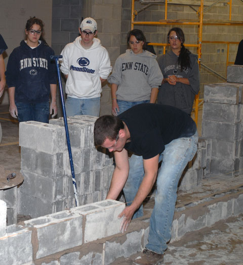 Penn State students get an abbreviated lesson in block-laying from Penn College's Zachary T. Bartlett.