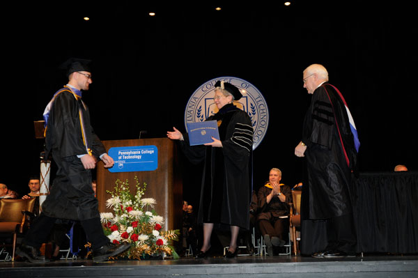 Student speaker Micah A. Metzel strides toward the outstretched hand of college President Davie Jane Gilmour.
