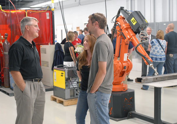 Welding instructor Mike Nau talks with alumnus Bill Berry and his wife, Heather.
