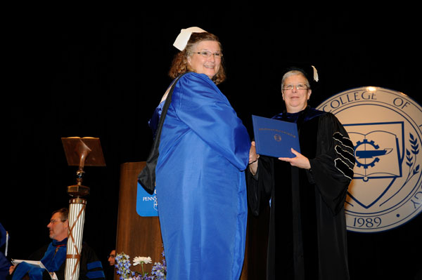 A nursing grad, in appropriate headgear, with college President Davie Jane Gilmour.