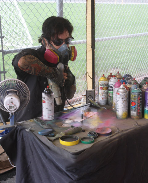 A spray-paint artist displays his craft for students.