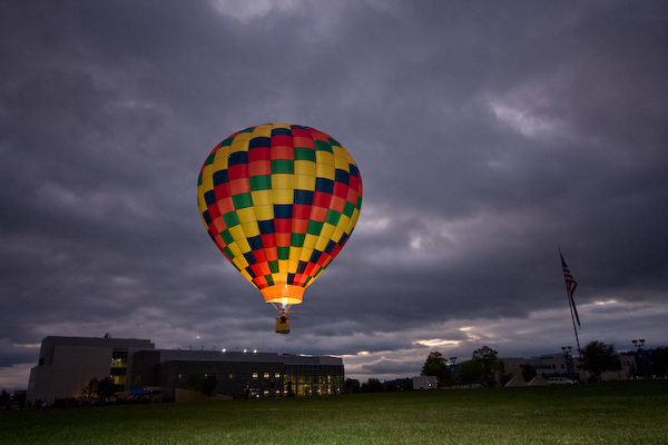 Balloon rises in colorful contrast against an ominous evening sky.