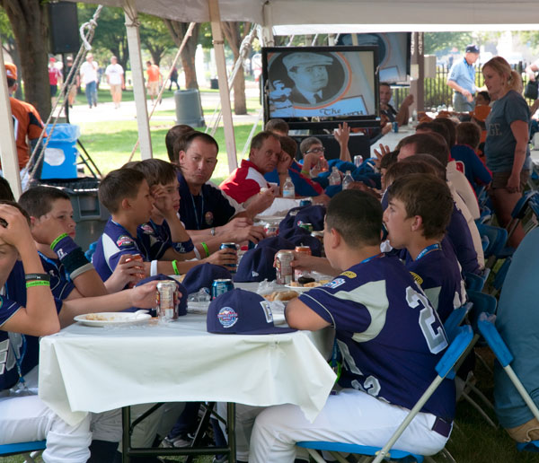 Players fill tables under the tent, as baseball-themed video clips are screened overhead.