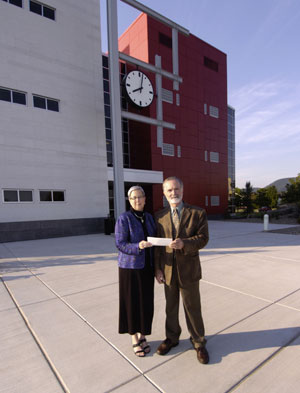 Pennsylvania College of Technology President Davie Jane Gilmour accepts a check from Donald E. Stringfellow, regional community relations director for PPL, in front of the Roger and Peggy Madigan Library