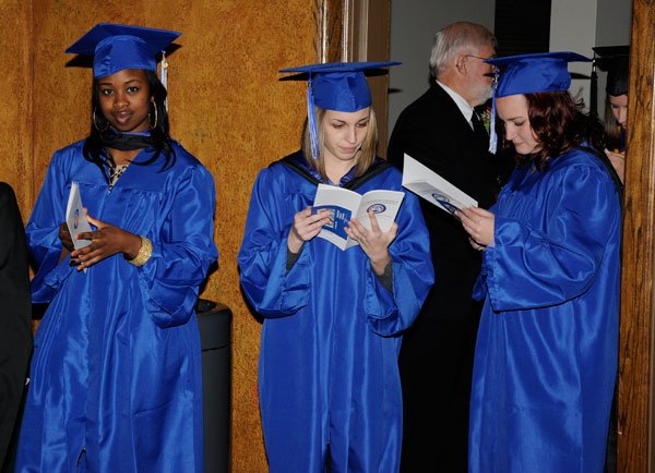 Students pass the time by thumbing through the official commencement program.