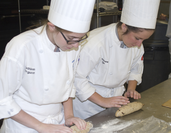 Baking and pastry arts students Kathleen Ferguson and Chelsea Igo prepare an artisanal raisin bread during a visit by representatives by the California Raisins Marketing Board.