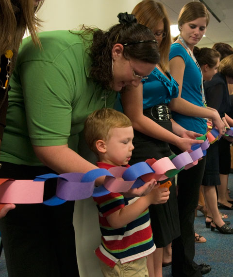 Early childhood education students assist a Childrens Learning Center client in cutting a paper-chain ribbon to open the colleges new early childhood education and child-care facilities.
