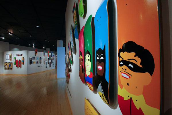 A cross-cultural sampling of superheroes lines a gallery wall.