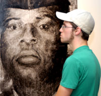 Luke Caputo, a graphic design student, admires the work of Leonard Ragouzeos, whose paintings will be on display at The Gallery at Penn College through Sept. 17.