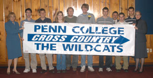 The men's and women's cross country teams get a little help from their friends (Dr. Jill Landesberg-Boyle, vice president for student affairs%3B athletic director Mike Stanzione%3B and Dr. Gilmour) in hoisting their banner.