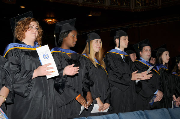 Graduation candidates rise for the conferral of degrees.