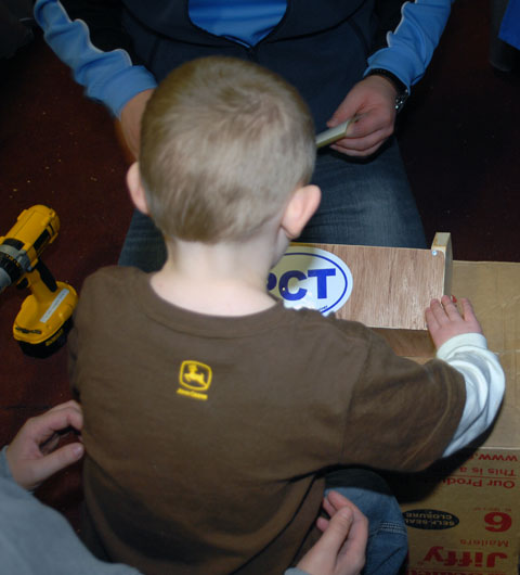 A young woodworker applies the finishing touch  a Pennsylvania College of Technology decal  to his handcrafted creation.