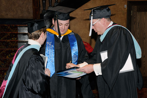 Friday's student speaker Adam J. Yoder gets some last-minute guidance from Carolyn R. Strickland, assistant vice president for academic services, and Elliott Strickland, interim chief student affairs officer.