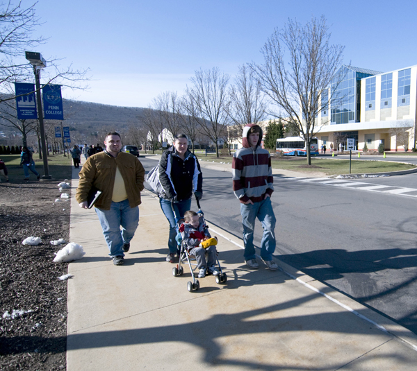 A family strolls along a Park Street sidewalk near the Bush Campus Center.