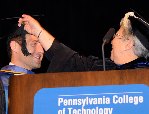 President Davie Jane Gilmour turns the tassel of class representative Andrew R. Christoffel, signifying his status as college graduate. 