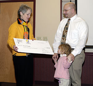 Trent Wright (and his young daughter) accept a %247,500 check from Mayor Mary B. Wolf.