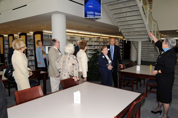 President Gilmour points out Madigan Library artwork hanging from a first-floor ceiling.