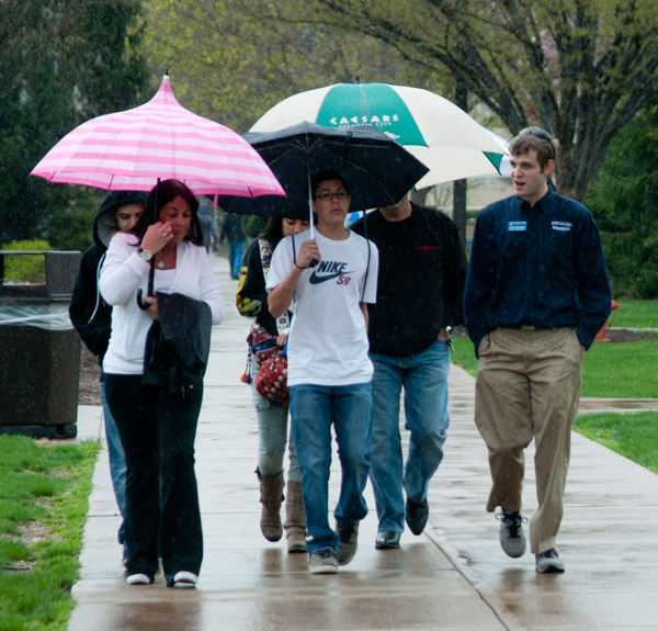 Umbrellas and hoodies raised against the day's scattered showers, Open House visitors  including this group with Student Ambassador Steven E. Dannenhower  persevered in completing their day's activities.