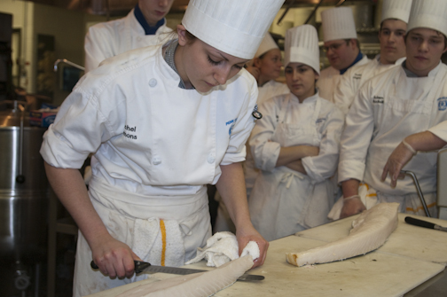 Culinary arts and systems student Rachel Emmons scales a sea bass.