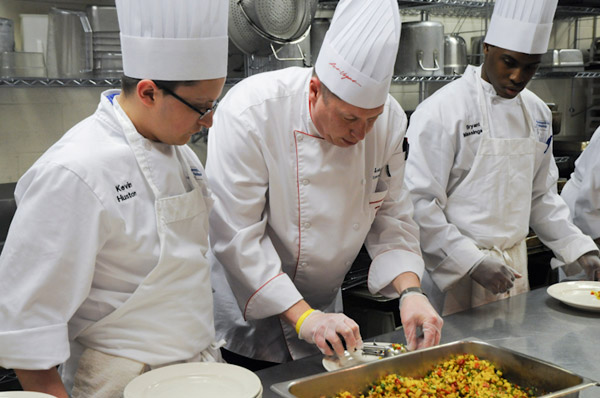 Students take direction for their role in the plating of the appetizer course.