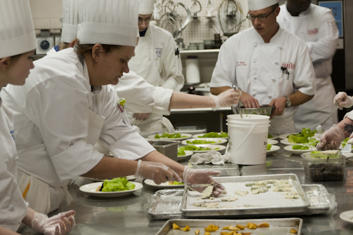 Hospitality management student Lily McDaniel adds blue cheese to a salad plate.