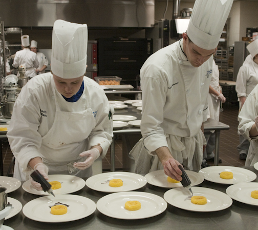 Baking and pastry arts student Rebekah Williams and baking and pastry arts/culinary arts instructor Chef Charles Niedermyer add flavor to a dessert plate.