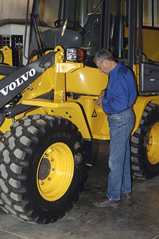 A technician makes an adjustment to a compact wheel loader.