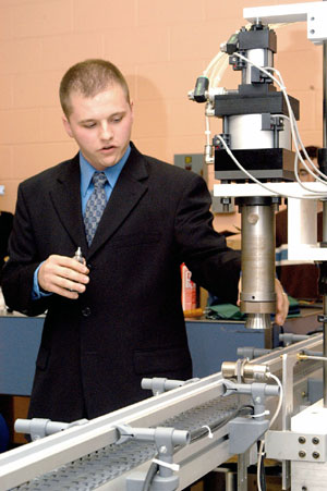 Chad E. Wagner touches a collet, which lowers to crimp the metal valve onto the glass perfume bottle.