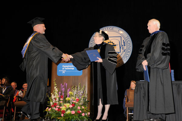 Walter V. Gower, assistant professor of aviation, is congratulated by college President Davie Jane Gilmour upon earning his bachelor's degree in aviation maintenance technology.