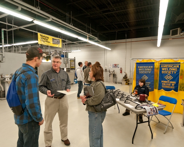 Welding instructor Mike Nau talks with a family in the Avco-Lycoming Metal Trades Center.