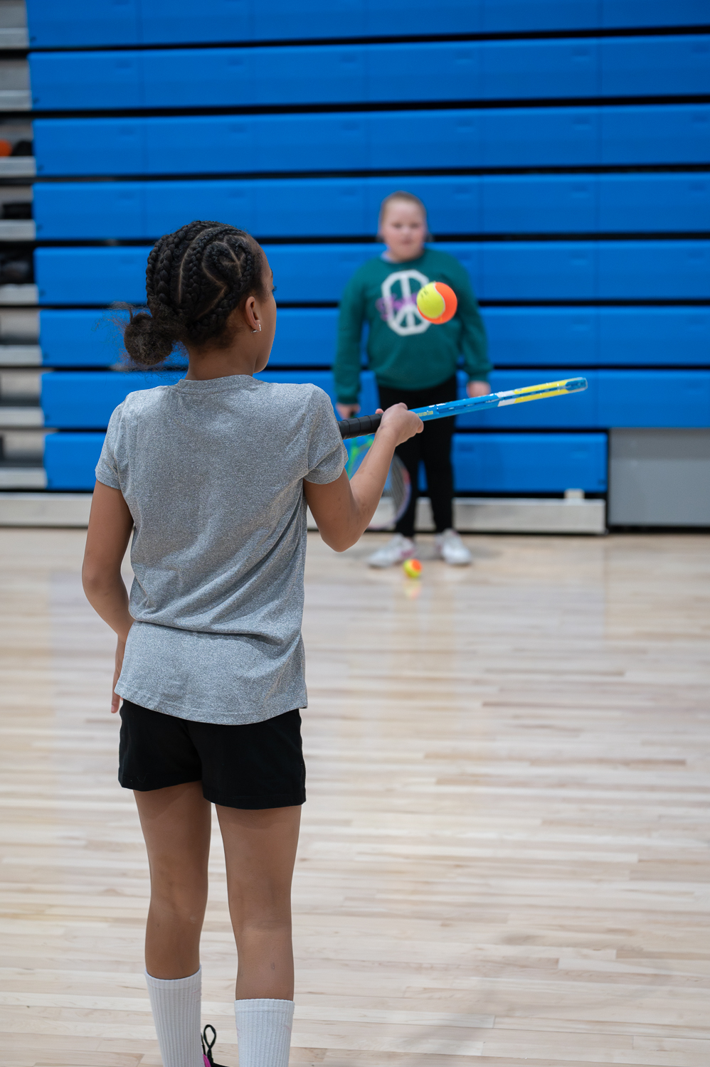 A girl bounces a tennis ball on a racket.