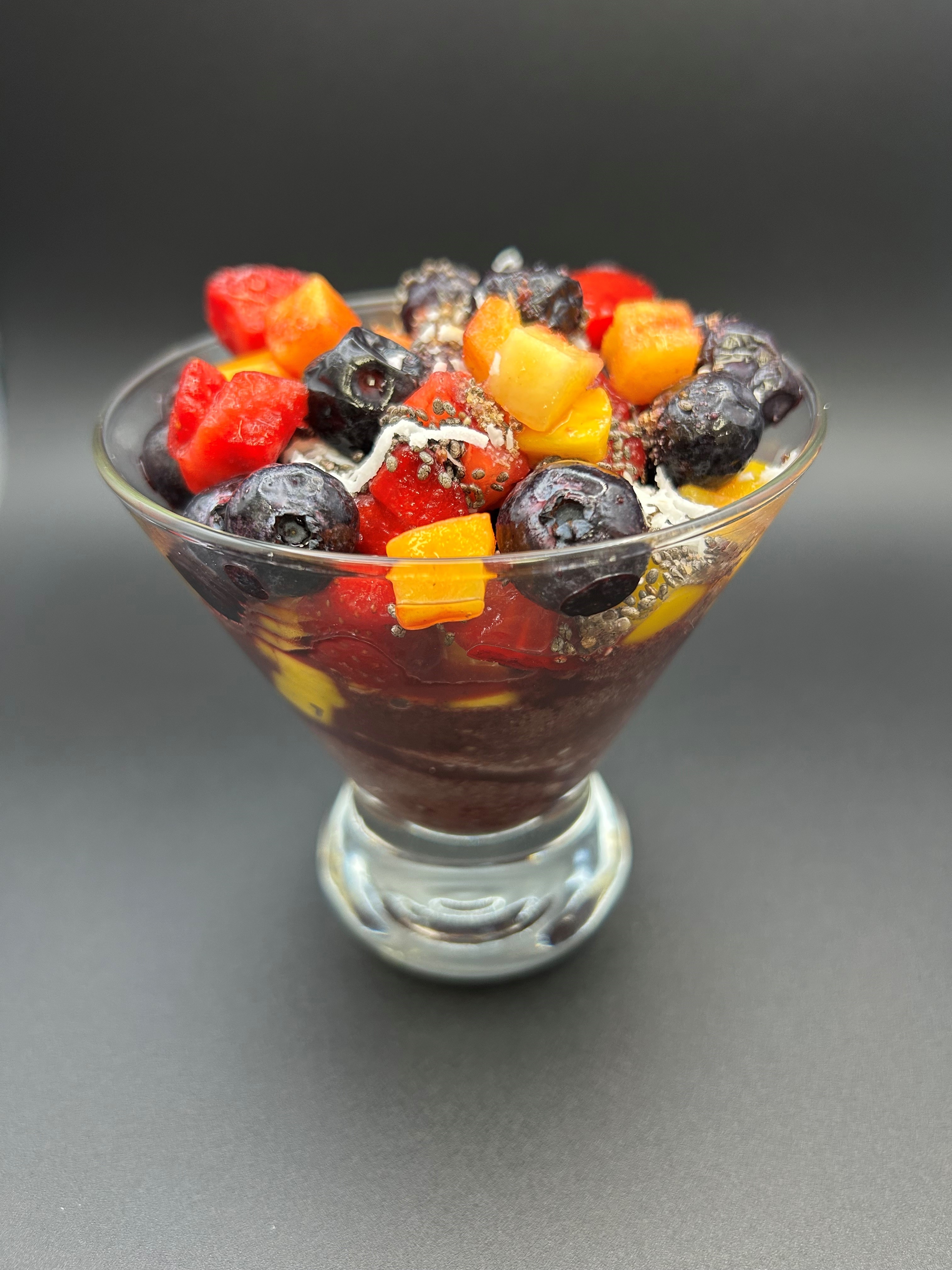 Glass bowl of fresh fruit, including acai berries.