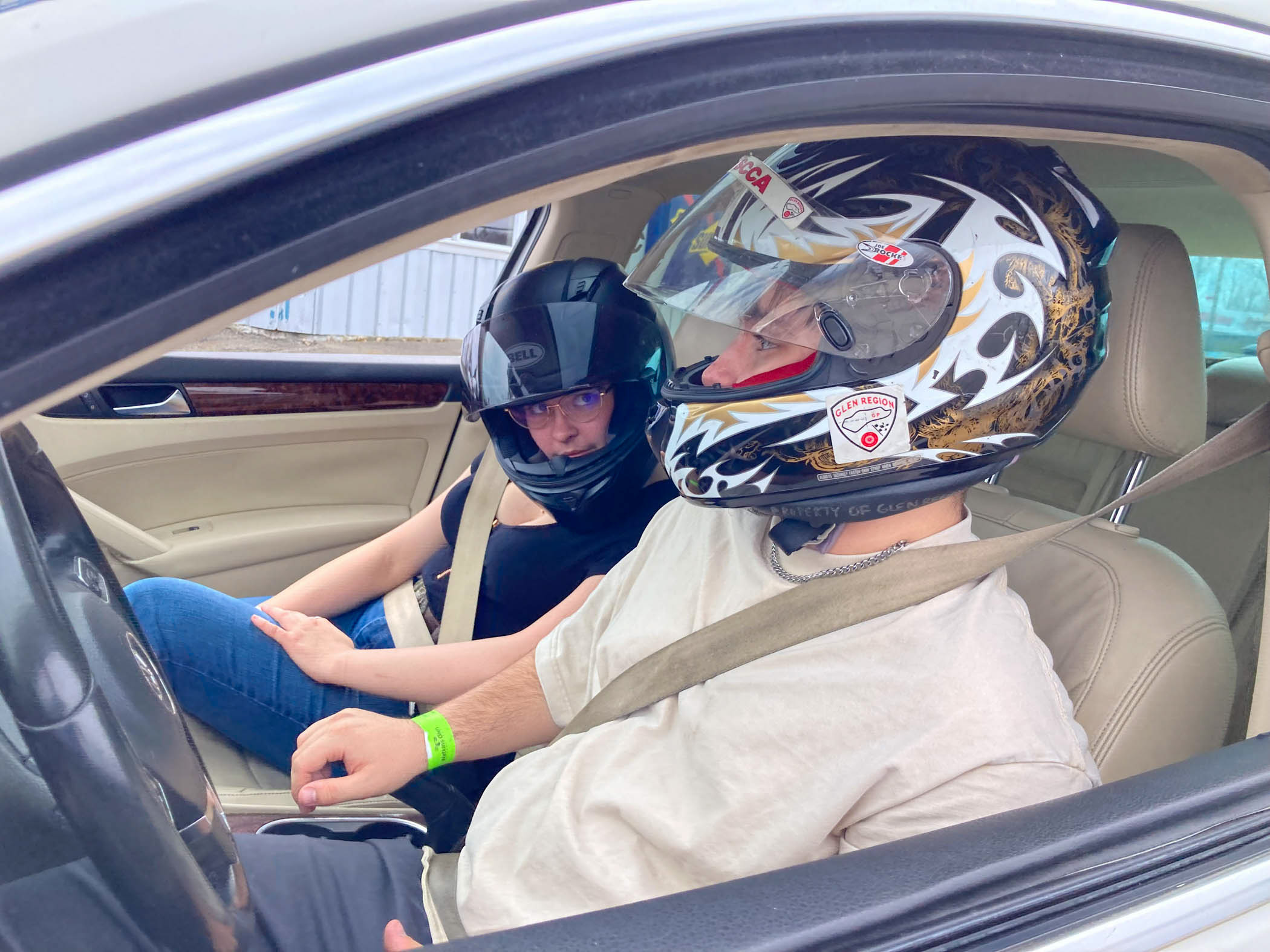 Two students in racing helmets sit inside a car.