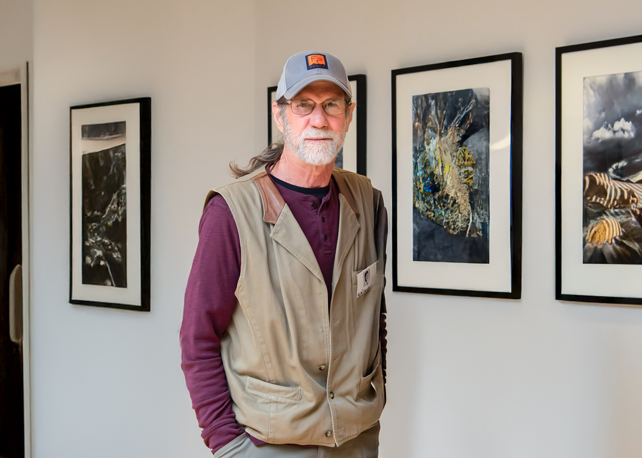 Keith Vanderlin stands in front of artwork on a gallery wall.