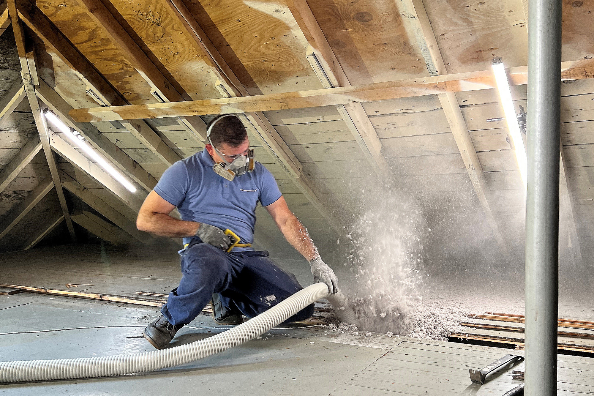 man blowing insulation in attic
