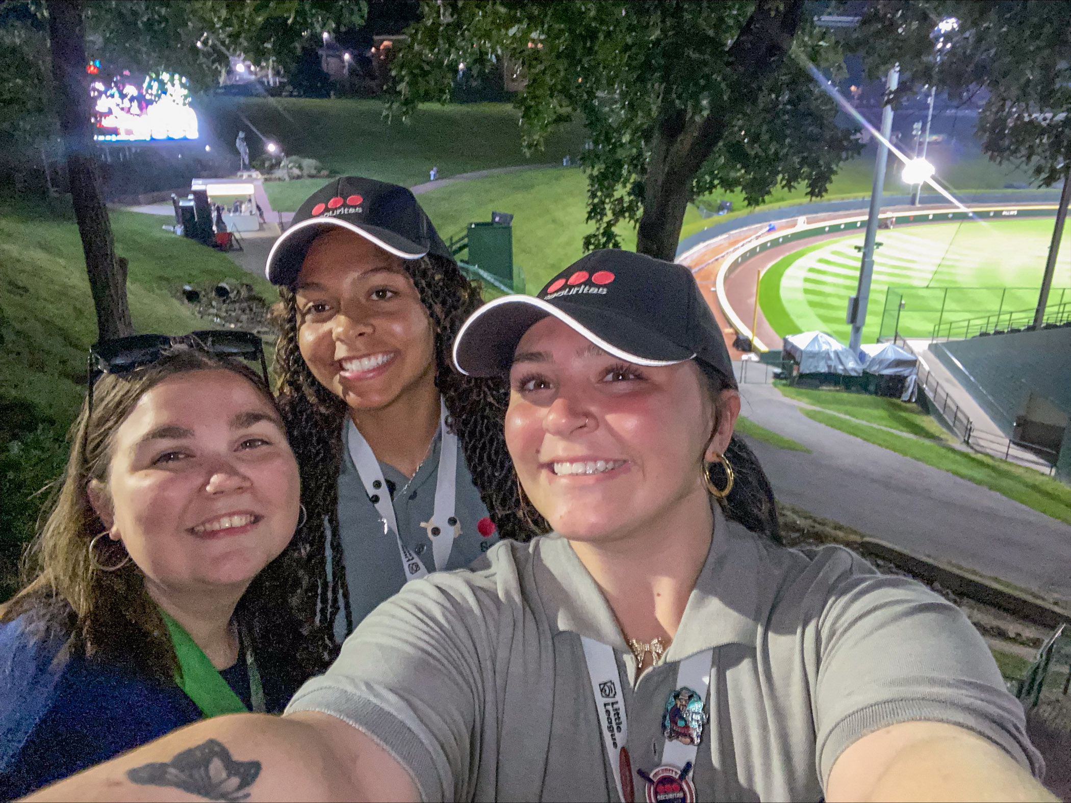 Three students take a selfie with a baseball stadium in the background.