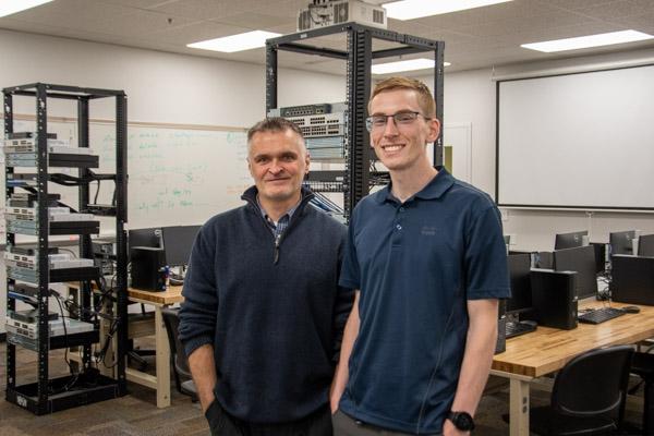 Stephen R. Cheskiewicz, associate professor of computer information technology, joins 2019 grad Anthony S. Riegel in the college’s recently updated networking lab before Riegel offered real-world perspectives to students in a capstone class.