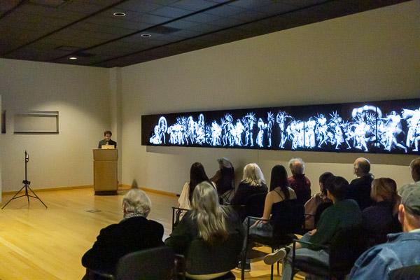 Singletary addresses the crowd alongside his work, which shines through the subdued lighting. 