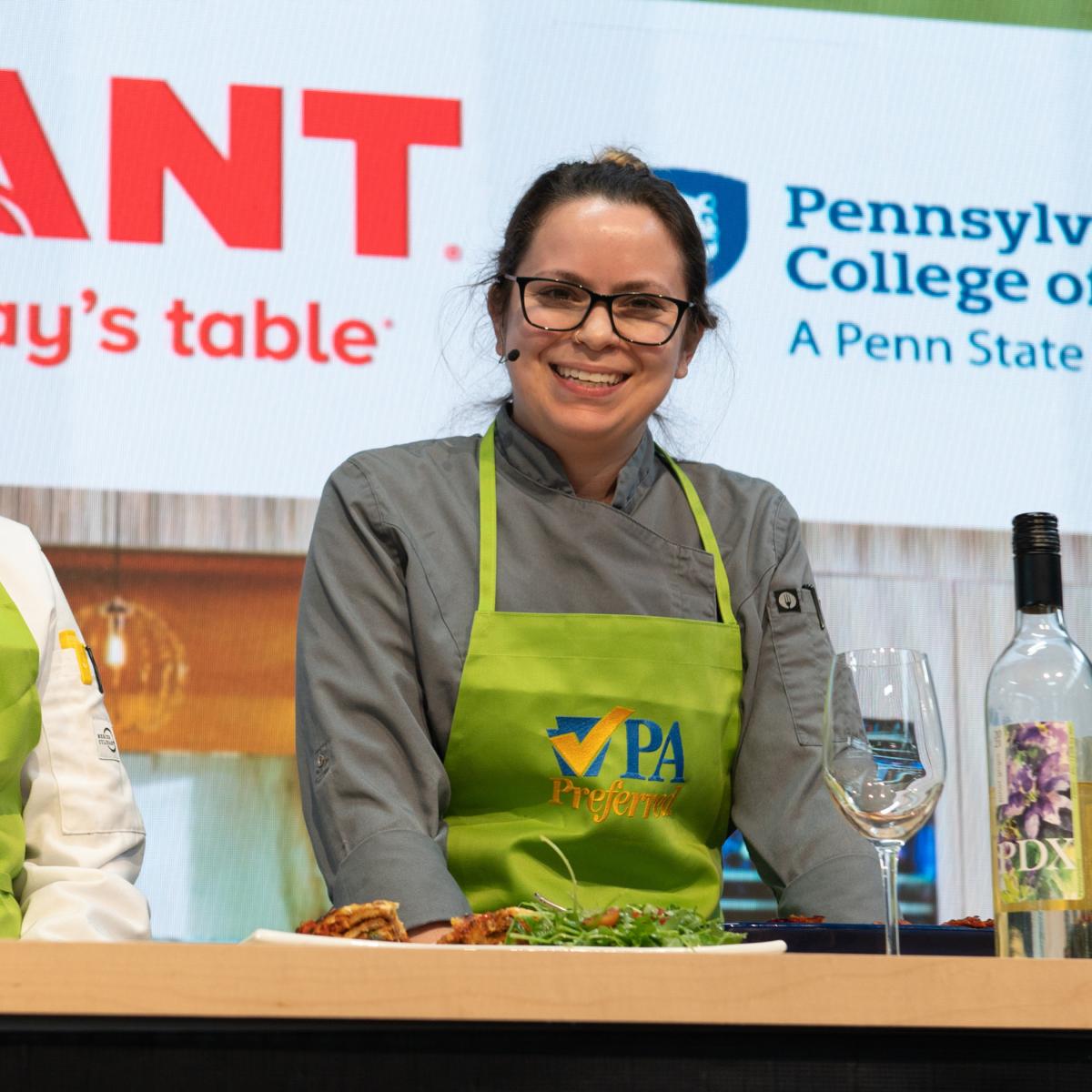 Kristina Wisneski, a Pennsylvania College of Technology culinary arts graduate, Food Network “Chopped” champion and sous chef at Pure Roots Provisions in King of Prussia, takes the stage at the 2023 Pennsylvania Farm Show. She will return to the college to mentor students in preparing the April 14 Visiting Chef dinner. (Photo by Kat Kuo for the 2023 PA Preferred® Culinary Connection at the Pennsylvania Farm Show)