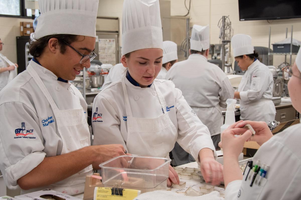 Baking & pastry arts students Christopher J. Macdonald, of Emmaus, and Hope G. Lomarro, of Exton, count liners that would later be filled with bite-sized salted caramel brownies.