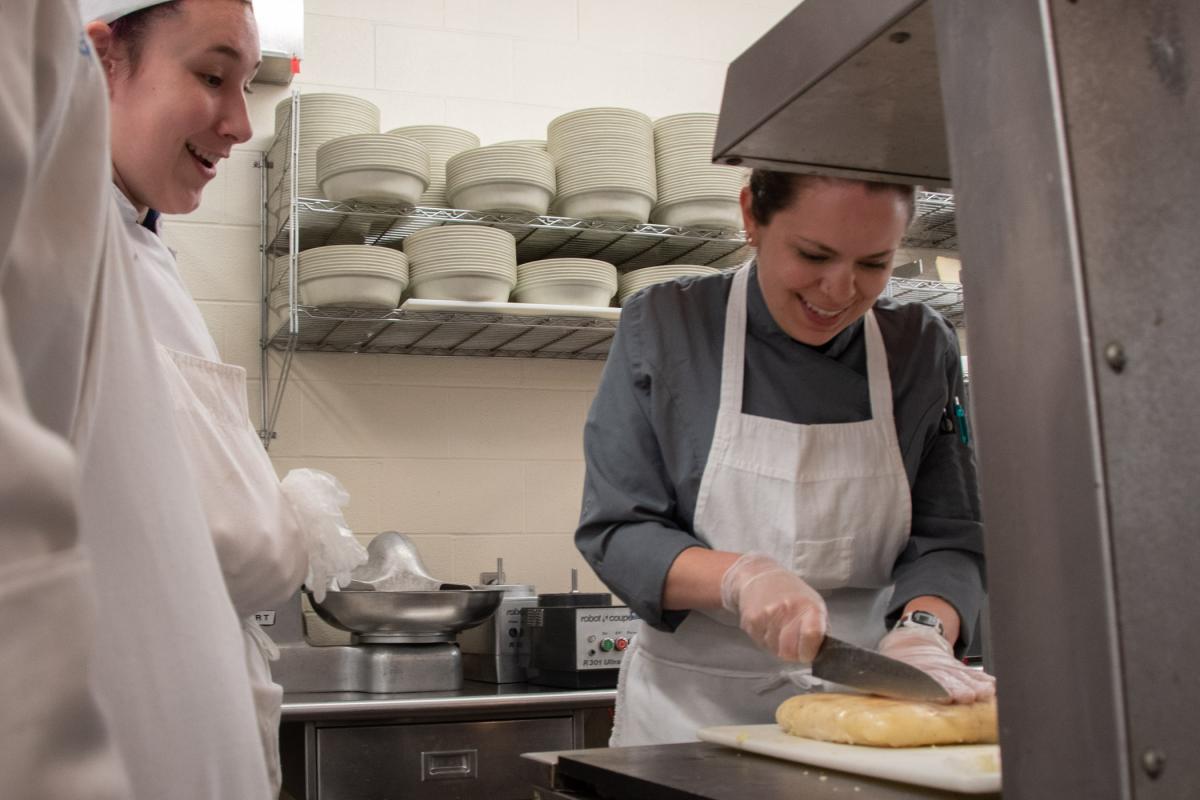 Wisneski shares smiles with Maddi H. Smith, of York, while demonstrating how to slice potato pave (which would later be fried and served with short rib). Smith is in the culinary arts technology major.