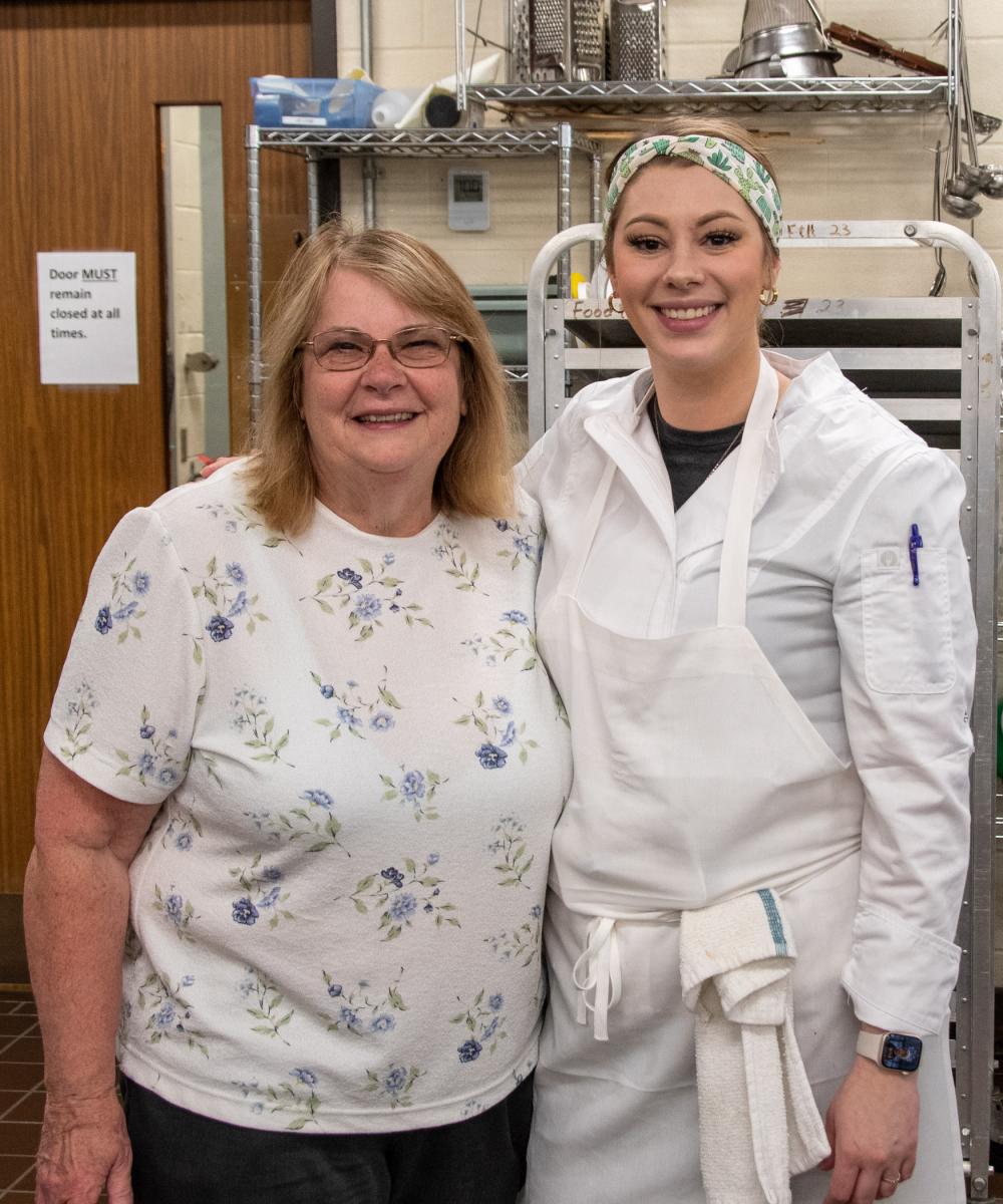 Sue L. Mayer, a retired assistant professor of baking & pastry arts/culinary arts – and a current part-time instructor – stops in to visit with her former student, Summa, in the baking lab.