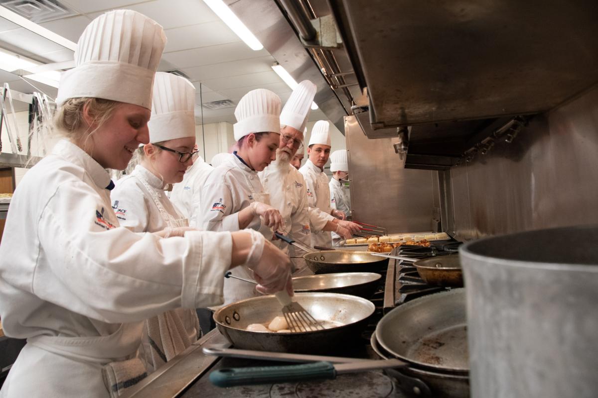 Searing scallops, under the watch of Chef Frank M. Suchwala, associate professor of hospitality management/culinary arts, are (from left): Alicia L. Walters, Osceola, culinary applications; Audrey N. Grello, State College, culinary arts technology; Maddi H. Smith, York, culinary arts technology; Suchwala; and Kade N. Chrostowski, of Moorestown, N.J. (frying potato pave), culinary arts technology and applied management.